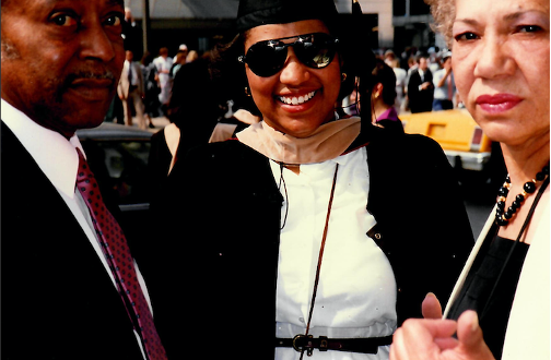 Lydia York, wearing sunglasses in cap and gown, standing outside between her parents on graduation day, Florida A&M University.
